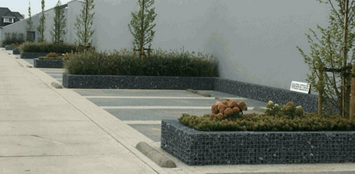 Parkeervakken gemarkeerd met schanskorf bloembakken.