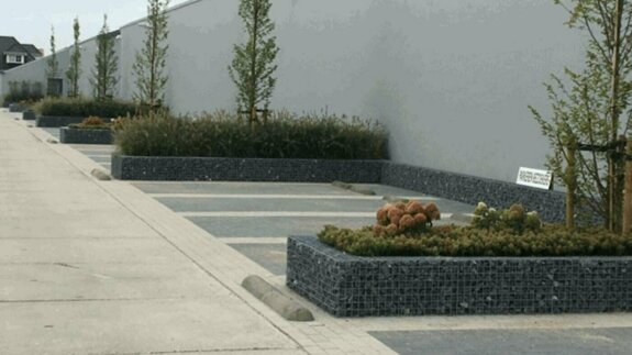 Parkeervakken gemarkeerd met schanskorf bloembakken.