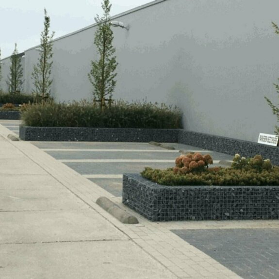 Parkeervakken gemarkeerd met schanskorf bloembakken.